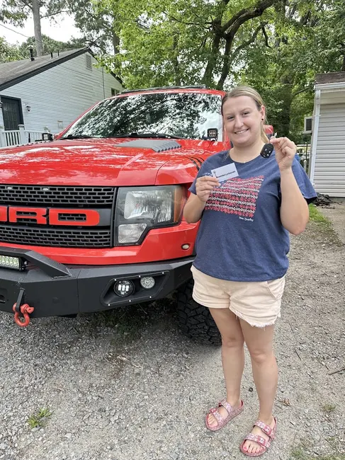 Customer receiving a replacement car key beside a red pickup truck